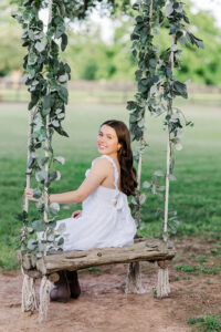Senior girl on swing under trees at farm in Houston.
